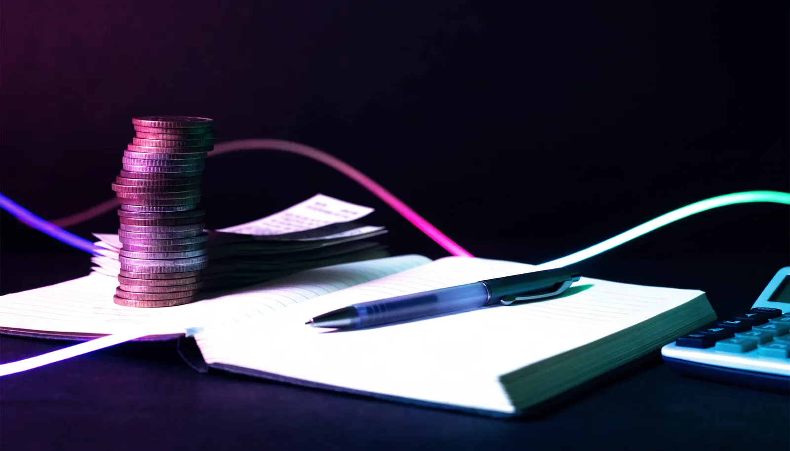 Carnet, pièces et calculatrice sur une table sombre